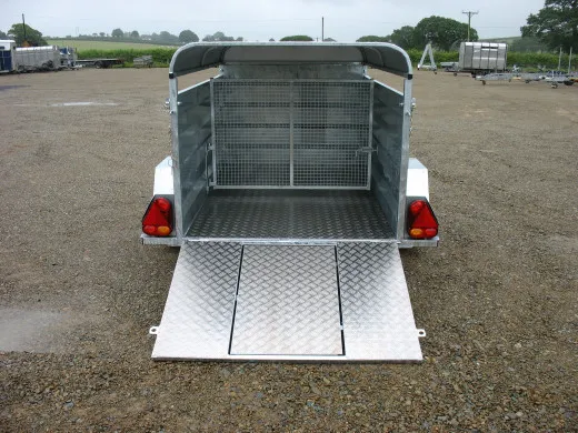The trailer from the rear with its ramp down, showing the mesh inner gate and the road lights