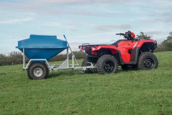 The snacker side-on behind a quad, showing the hopper and the galvanised frame it sits in
