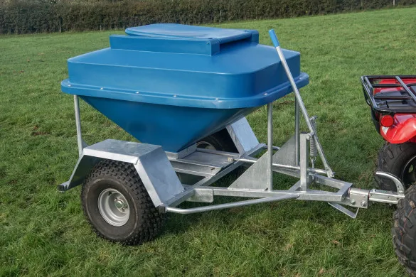 A CLH snacker feeder with a blue hopper on a galvanised chassis, towed by a quad