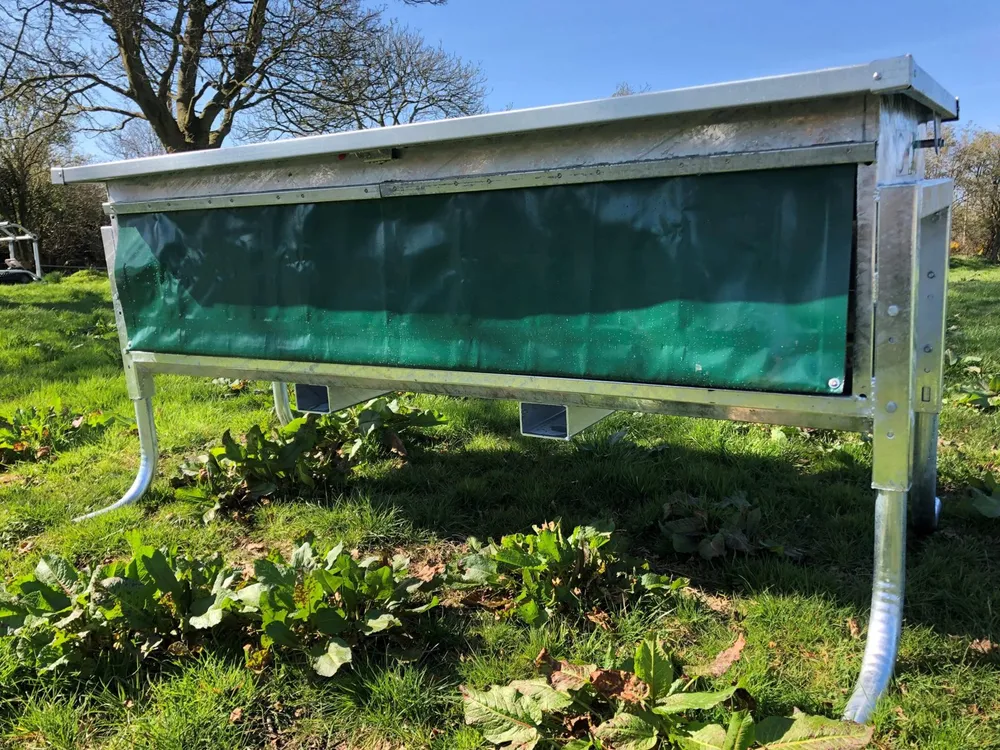 A stainless steel Condon calf feeder in a field