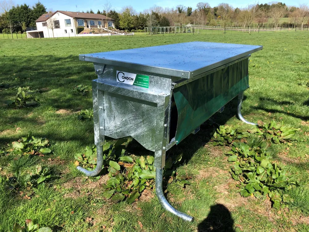 The feeder from the front, showing the hinged galvanised lid and the calf-sized gap at the end