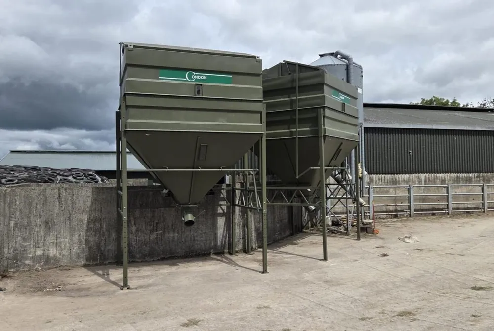Two twelve-tonne bins painted green, standing side by side next to an older silo