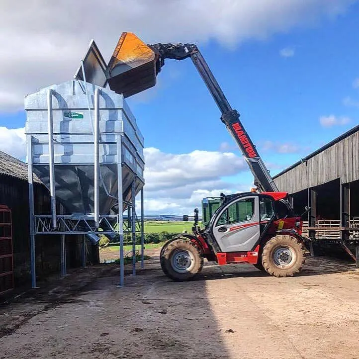 A Manitou telehandler tipping meal into the bin from above