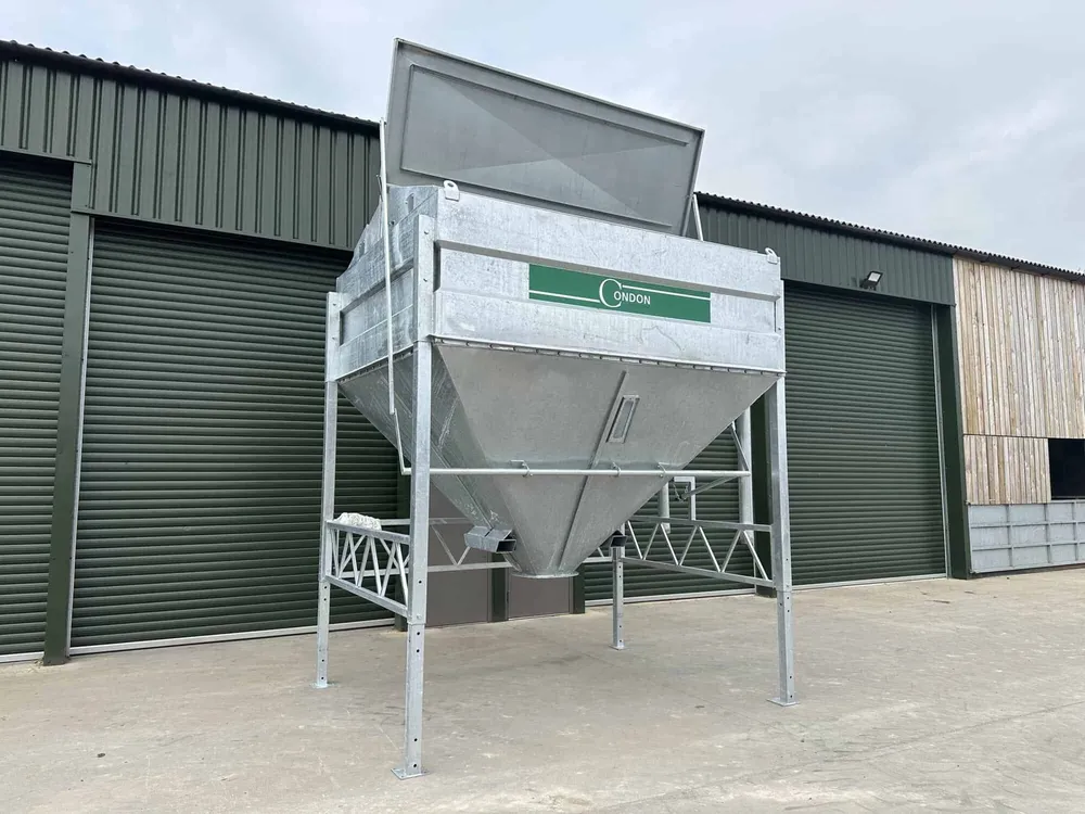 The eight-tonne bin with its lid propped open, standing on adjustable legs in a concrete yard