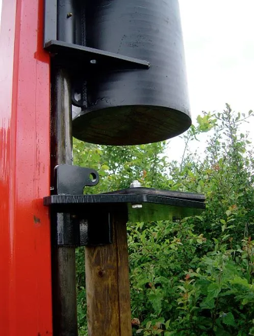 The black driver weight raised above a wooden post, with the mast in front of a hedge