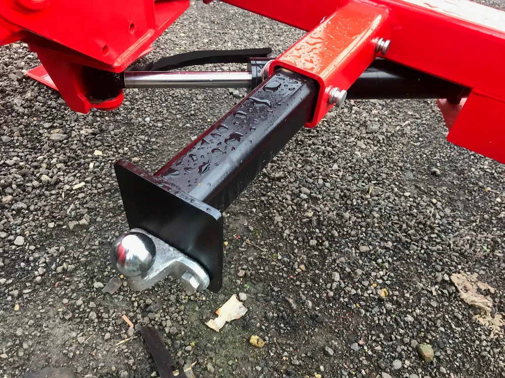A hydraulic ram on the frame, extended, with a tow ball mounted on the end plate